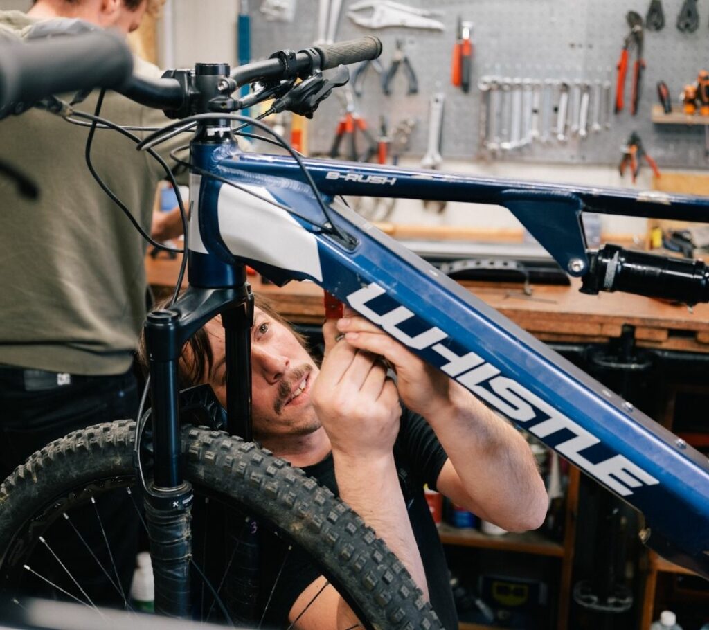 Julien de LE VELO ROUGE travaillant sur un châssis de vélo dans l'atelier