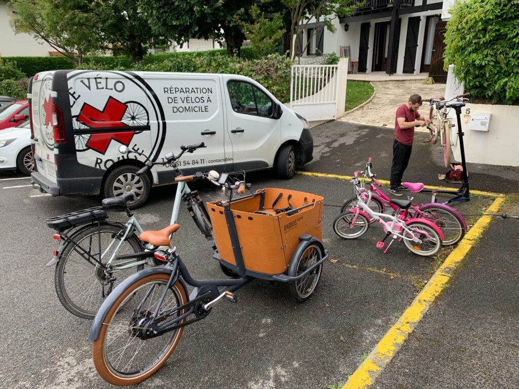 Technicien venu en camionnette Le Vélo Rouge réparant des vélos chez un client